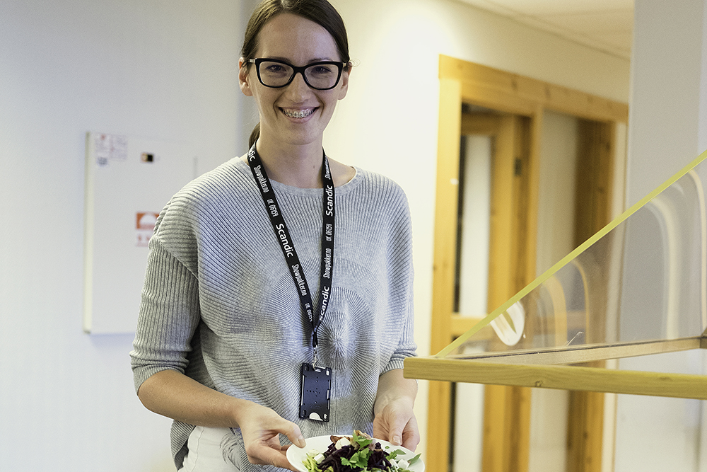 Ung glad dame med en skål med salat ved lunsjdisken på Kompetansesenteret